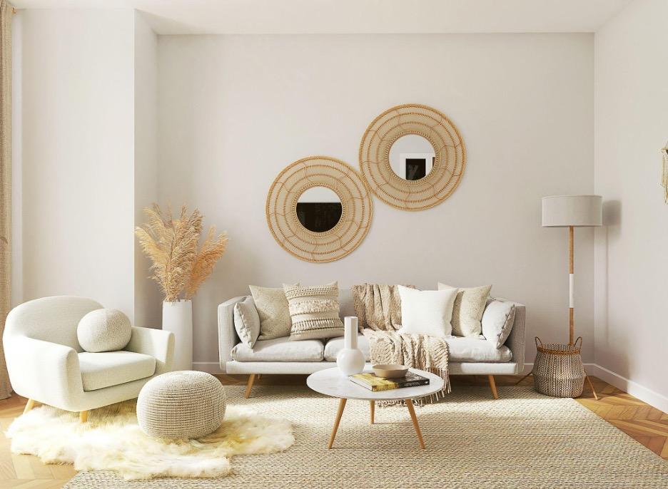 Bright neutral living room with a beige sofa, woven wall mirrors, soft textured furnishings, a round coffee table, and natural décor creating a calm, minimalist interior.