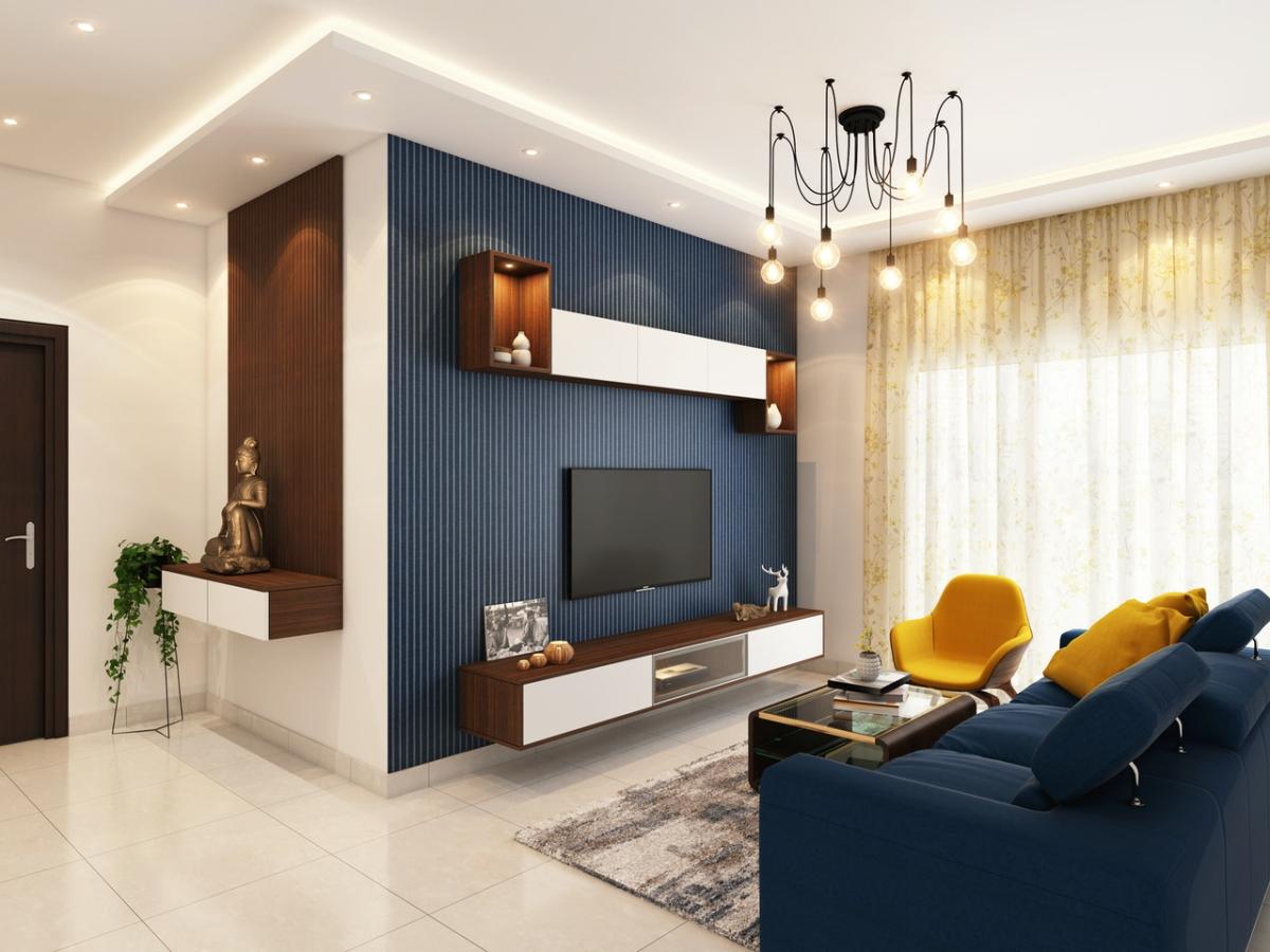 Modern living room with a wall-mounted TV, blue accent wall, contemporary shelving, pendant lighting, and a blue sofa with a yellow armchair near a large window.