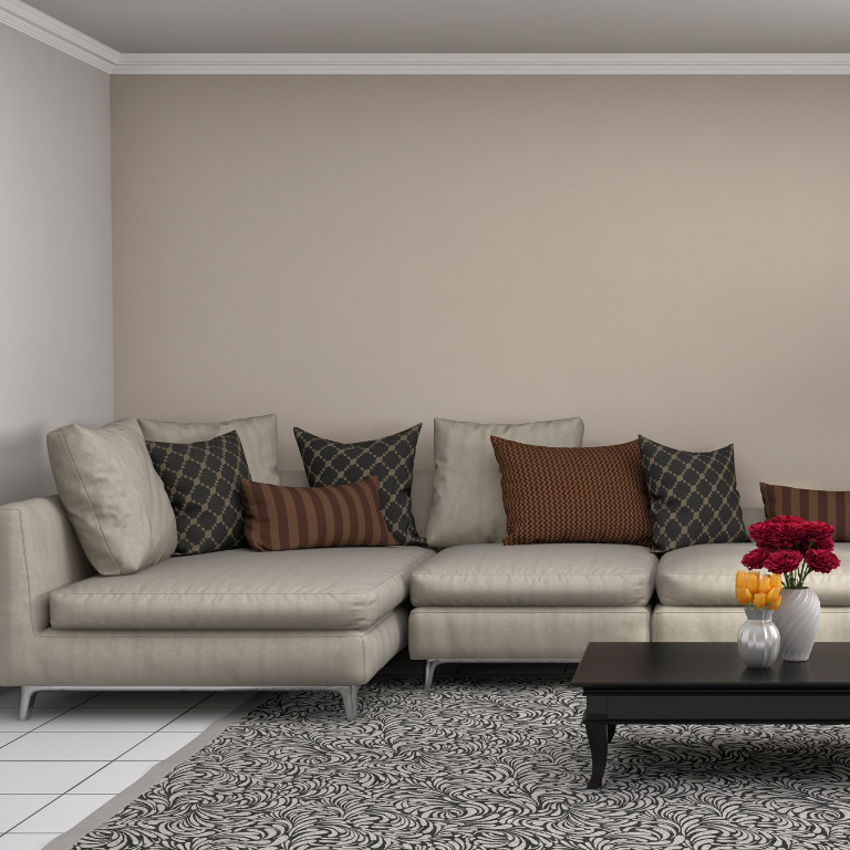Neutral-toned sectional sofa with patterned accent cushions in a minimalist living room, styled with a black coffee table, floral centerpiece, and textured area rug.