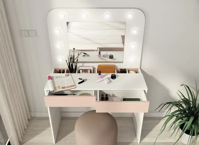 White vanity dressing table with light-up mirror, open drawer storage, makeup accessories, and a round upholstered stool in a bright bedroom.